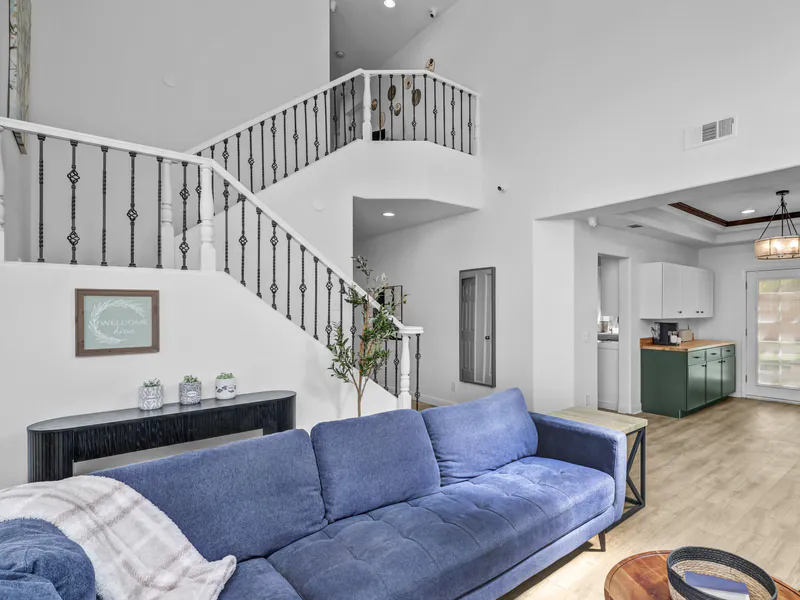 Entry hall with a framed Welcome home sign, a blue sofa and the staircase