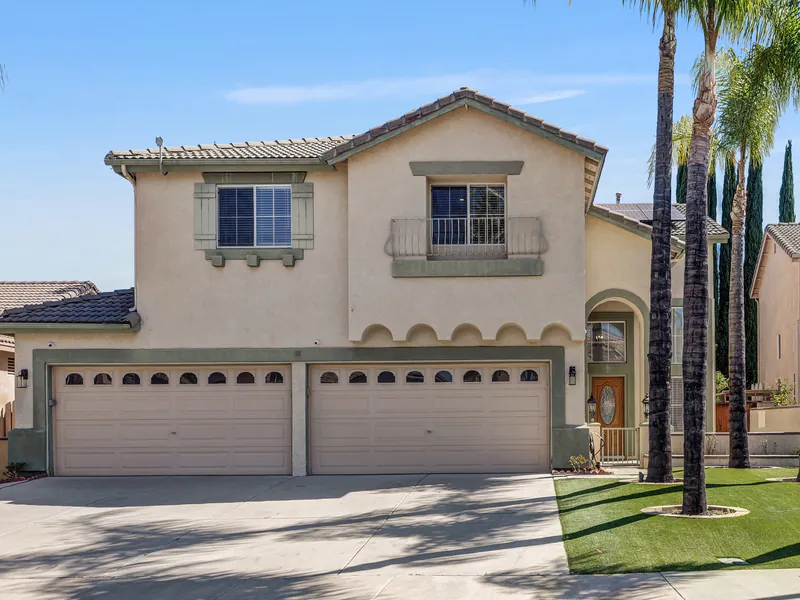 Front of the two-story home with palm trees